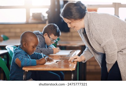 Teacher, woman and help kid for education, study or writing knowledge in notebook at class. Child, educator and student learning in lesson for development, teaching and support at kindergarten school - Powered by Shutterstock