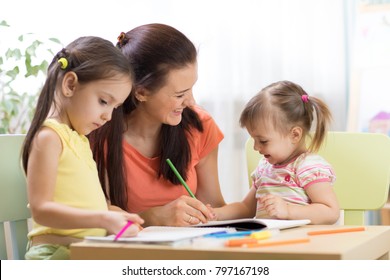 Teacher Working With Children Kids In Preschool Classroom