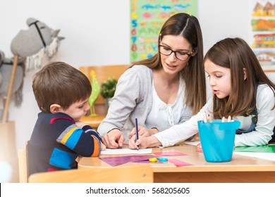 Teacher Working With Children In Preschool Classroom