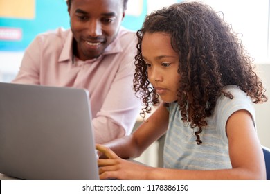 Teacher Working With Elementary School Girl At Laptop