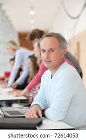 Teacher Working On Laptop Computer In Classroom