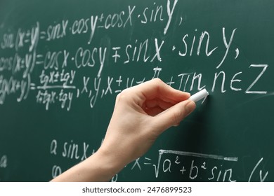 Teacher writing down math equation on green board, closeup - Powered by Shutterstock