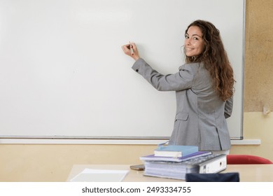 A teacher writing the new agenda for the day on the class blackboard. A businesswoman at the office board to propose her idea in team work. Young woman smiles looking at camera. - Powered by Shutterstock