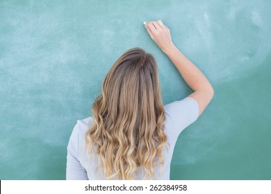 Teacher Writing On Blackboard In Classroom