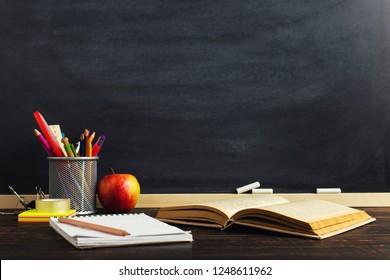 Teacher's desk with writing materials, a book and an apple, a blank for text or a background for a school theme. Copy space.