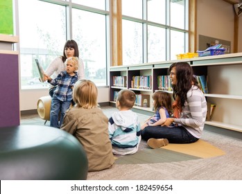 Teachers And Elementary Students In School Library