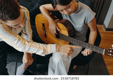 Teaching Guitar Chords to Female Music Learner on Couch - Powered by Shutterstock