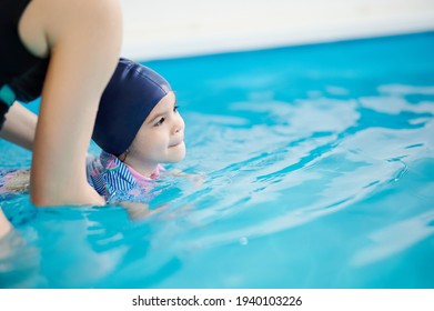 Teaching Kids To Swim Theme. Baby Girl Swimming With Teacher With Copy Space