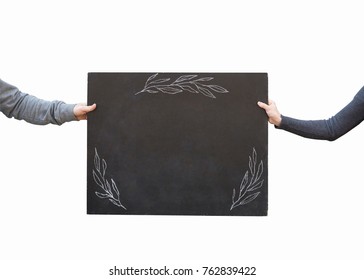 teaching  learning  background concept  isolated school blackboard and floral paintings and white chalk  it is held and two arms people that are dressed in grey sweatshirt
