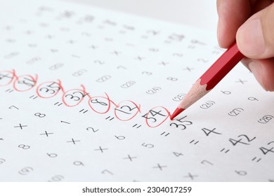 Teahcer's hand checking math test sheet with red pencil