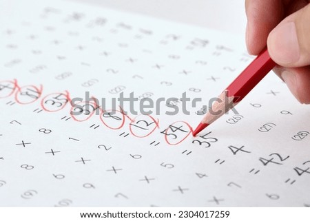 Teahcer's hand checking math test sheet with red pencil