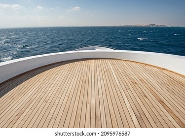 Teak bow deck of a large luxury motor yacht out at sea with a tropical ocean view background