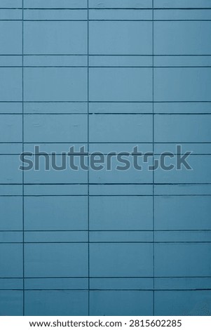 Teal blue architectural cladding panels forming a minimalist geometric grid on a modern building facade.