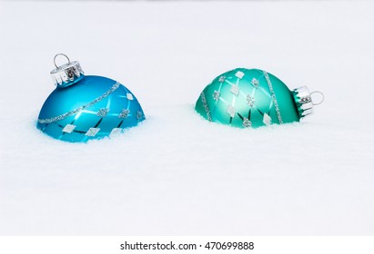 Teal Blue, Green And Silver Christmas Ornaments Buried  In Snow; White Copy Space