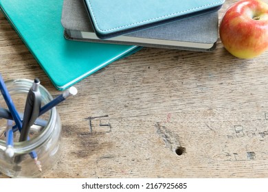 Teal Books And Jar Of Pens With Red Apple On Vintage Desk Top From Above With Copy Space