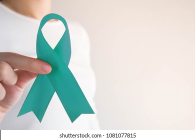 Teal ribbon awareness on female hands in white t-shirt background w/ copy space. Symbolic for cervical cancer, ovarian cancer, gynecological cancer and PCOS. Women's health care concept.