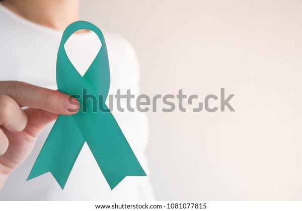 Teal ribbon awareness on female hands in white\
t-shirt background w/ copy space. Symbolic for cervical cancer,\
ovarian cancer, gynecological cancer and PCOS. Women\'s health care\
concept.