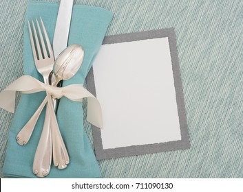 Teal Table Place Setting With Silverware, Cloth Napkin And Textured Turquoise Matt With A Menu Card With Room Or Space For Copy, Text, Or Words.  A Horizontal With Flay Lay, Top Overhead View.