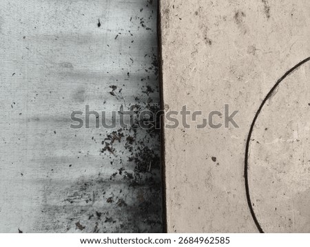 Teal-stained sheet and beige board split by a seam, with a faint hand-drawn circle cutting through dust, specks, and mottled wear.
