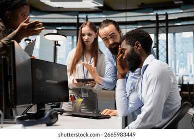 Team of admins collaborate to block hacking network intrusion affecting office equipment. IT expert and colleagues responding to live cyberattack warning popup on PC, neutralizing hacker breach