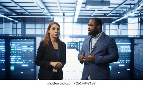 Team of admins in high tech data center looking at hologram visualization. Engineer and coworker working on securing serves using AR tech, preventing hacker attacks, camera B