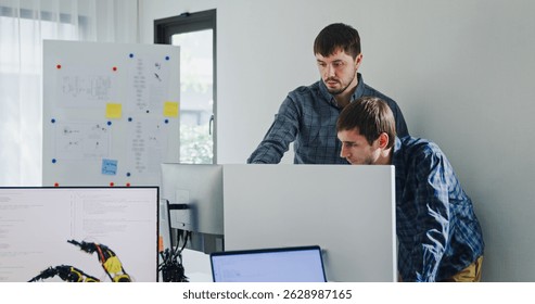 Team adult male engineer collaborate on robotic hand project using AI code solutions machine learning at tech workspace. Artificial intelligence interface, collaboration support prototype development.