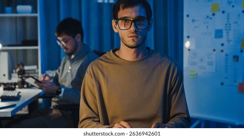 Team adult male freelance developer work late typing write prompt AI bot app program nomad terminal code at office night. Artificial intelligence dashboard, robotics, user interface, machine learning.