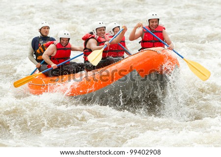 A team of adventurers paddle through the white waters of an extreme river on a thrilling rafting expedition, showcasing their outdoor teamwork.