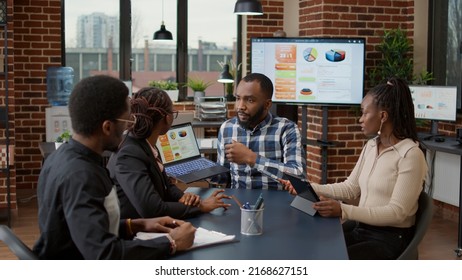 Team Of African American People Meeting In Office To Plan Business Strategy, Looking At Financial Charts On Laptop. Creative Colleagues Doing Collaboration On Project And Presentation For Development.