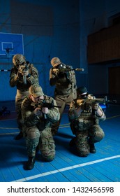 A Team Of Airsoft Players In The Old School Gym In Combat Positions