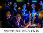 A team of analysts writing code by the glow of the screens inside a low-light innovation lab, showing modern teamwork, data and digital innovation with moody blue lighting.