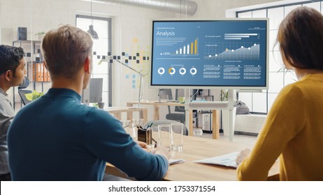 Team of Analytics, Economists, Young Businesspeople Hold Meeting Presentation use Shows Digital Interactive Whiteboard with Growth Analysis, Charts, Statistics and Data. People Work in Creative Office - Powered by Shutterstock