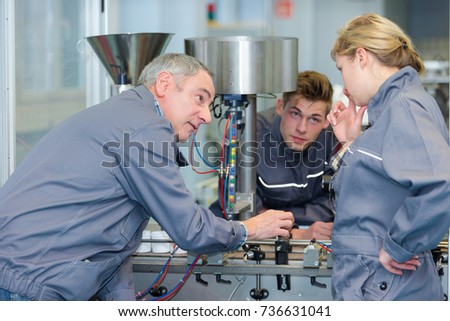 team of apprentices operanting a machine
