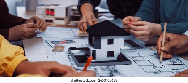 Team of architects engaged in a collaborative session, discussing building plans while showcasing a detailed model of a house, reflecting creativity and innovation. SACTR - Powered by Shutterstock - Get 15% off with code: PIKWIZARD15