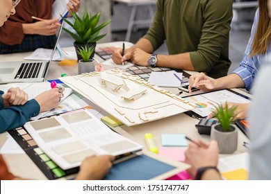 Team of architects and engineers working on urban building model scale. Hand of colleagues working on a house project. Close up of people hand working around prototype of a shopping center site. - Powered by Shutterstock