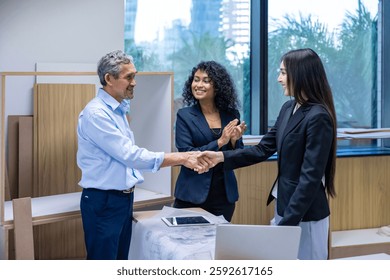 Team of architectures, engineer, interior designer and businessmen handshaking over finalize the floor plan modification for real estate renovating investment and housing development project concept