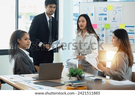 Team of asian business working with document paper sitting at desk in office in meeting room, Business team working with project statistics, Asian business team and present graphic info in room.