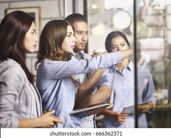 A Team Of Asian And Caucasian Business People Working In A Brainstorm Session Using Laptop Computer, Digital Tablet And Post-it Notes.