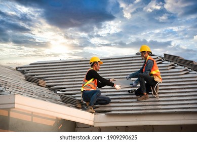A team of Asian engineers install the new CPAC roof, roofing tools, electric drill, and use it on the new roof with the concept of building CPAC roof houses