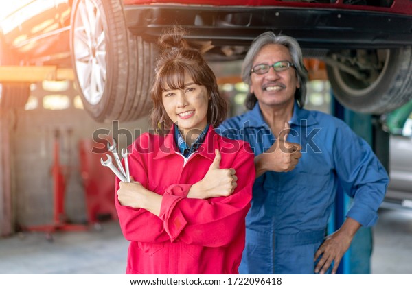 Team of\
Asian Mechanics Smiling and Giving Thumb Up. Woman and Man Mechanic\
Car Repair Worker in the Auto Repair. \
