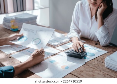 Team of asian people taxation bookkeeper consulting with friends analyzing balance sheet company annual financial report, tax of stock market statement in modern office. using calculator