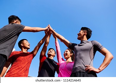 team of asian young adult sportsmen and sportswoman putting hands together to show unity and teamwork spirit. - Powered by Shutterstock