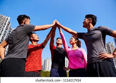 Team Of Asian Young Adult Sportsmen And Sportswoman Putting Hands Together To Show Unity And Teamwork Spirit.