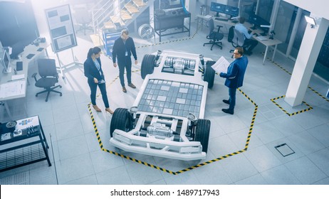 Team of Automobile Design Engineers in Automotive Innovation Facility. They are Working on Electric Car Platform Chassis Prototype that Includes Wheels, Suspension, Hybrid Engine and Battery.
