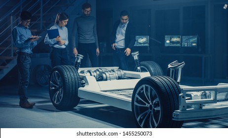 Team of Automotive Engineers Discussing and Designing Electric Car Platform Chassis Prototype, Taking Measures, Working with 3D CAD Software, Checking Quality Control. Vehicle Frame with Wheels - Powered by Shutterstock