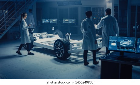 Team Of Automotive Engineers And Scientists Discussing, Designing And Working On Electric Car Platform Chassis Prototype. Using 3D CAD Software, Analysing Efficiency. Vehicle Frame With Wheels