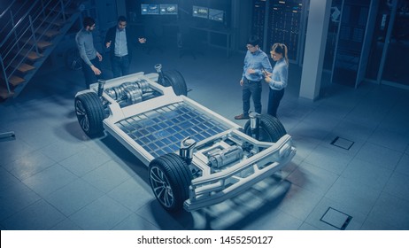 Team of Automotive Engineers Working on Electric Car Chassis Platform, Taking Measures, working with 3D CAD Software, Analysing Efficiency. Vehicle Frame with Wheels, Engine and Battery.