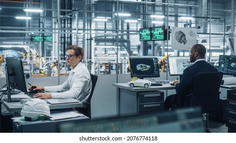 Team Of Automotive Engineers Working On Desktop Computers In Modern Office At Car Assembly Plant. Industrial Product Designer Developing Electric Engine Parts With Colleagues At Vehicle Factory.