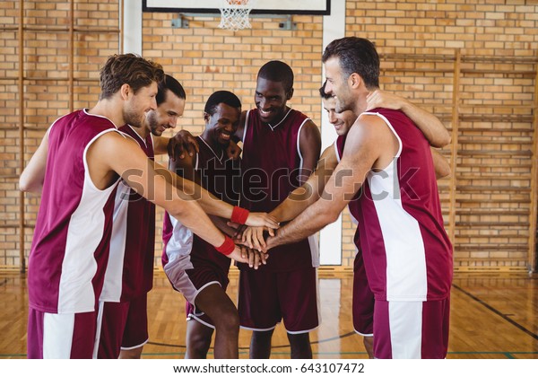 Team of\
basketball players stacking hands in the\
court