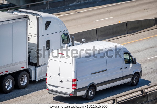 Team of Big rig semi
truck with dry van semi trailer and compact cargo mini van driving
side by side on the multiline highway road working hard together
for timely delivery